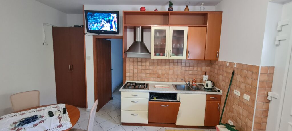 Opremljena kuhinja s TV in jedilnim kotom v apartmaju Strunjan